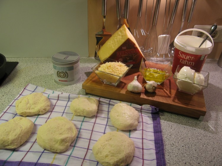 Zutaten für 4-6 Stück: 200 ml Milch, 1 TL Zucker, 20g frische Hefe, 250 g Kartoffeln, gekocht, 100 g glattes (sehr feines) Mehl, 400 g griffiges (etwas gröberes) Mehl, 1 TL Salz, 400 ml Sonnenblumenöl, 2 Knoblauchzehen