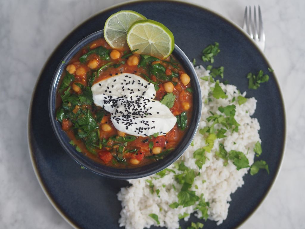 Kichererbsen-Tomaten-Curry mit Seewinkler Reis mit einer unter dem Teller hervorlugenden Gabel