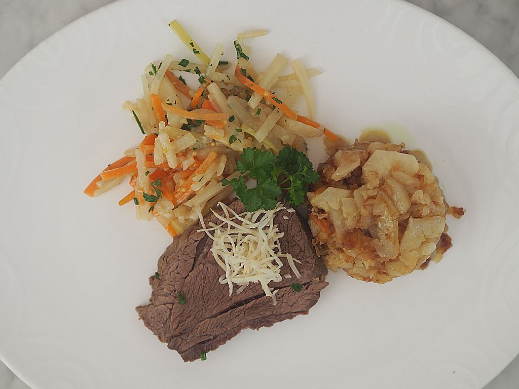 Beinfleisch mit Wurzelgemüse und Topinambur-Rösti auf einem weißen Teller