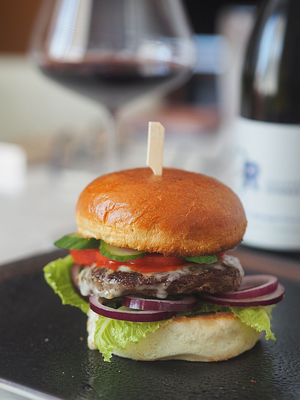 Burger und Rotweinflasche im Hintergrund