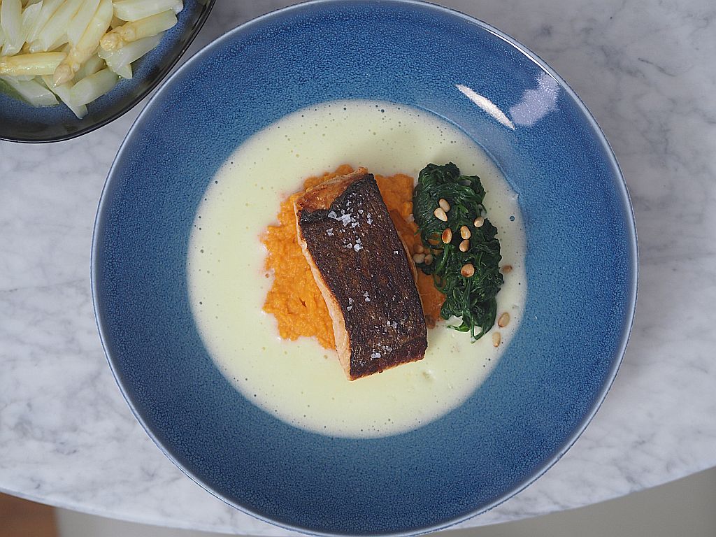 Lachs mit Süßkartoffelstampf, Spinat und Sauce hollandaise au einem blauen Teller