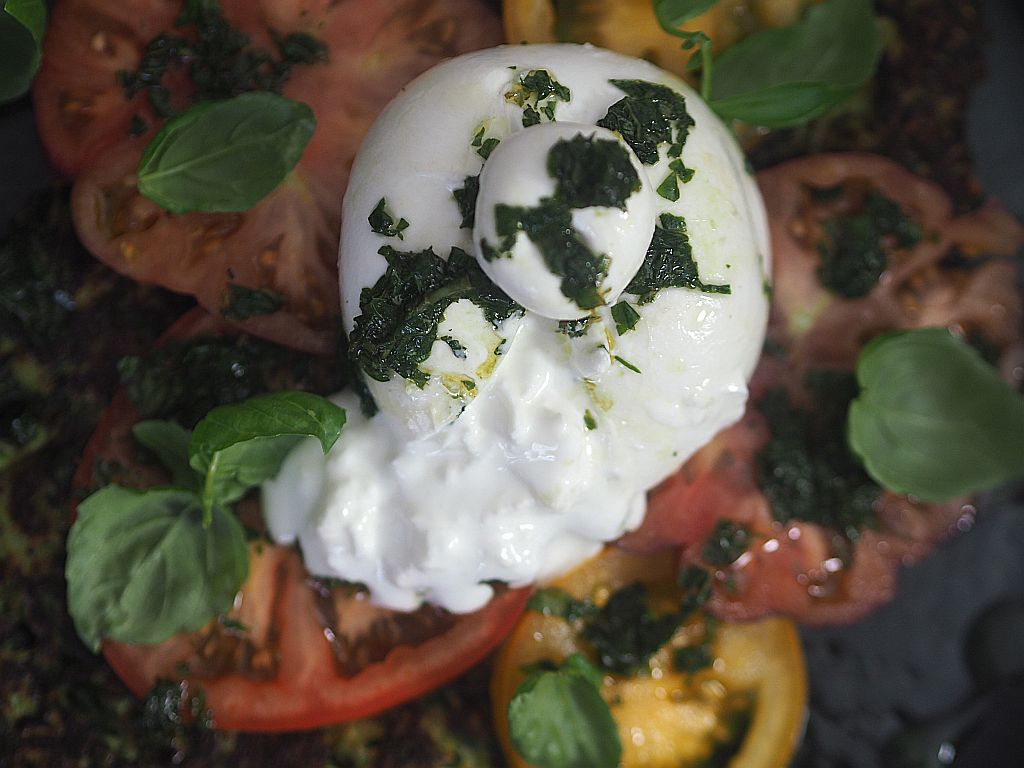 Burrata di Bufala, aufgeschnitten, ergießt sich über die Tomatenscheiben