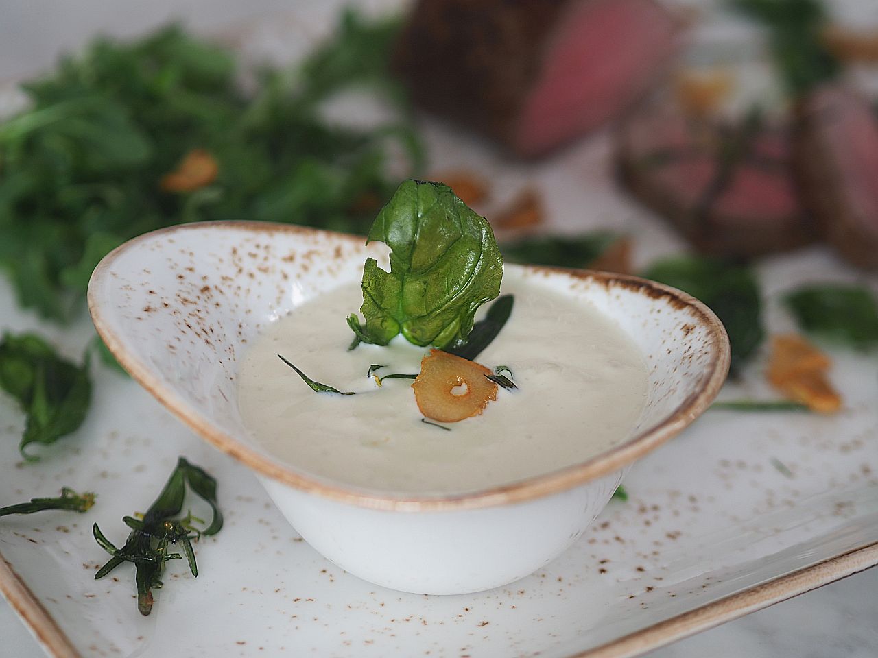 Vitello tofunato mit fritierten Knoblauchscheiben und Kräutern.