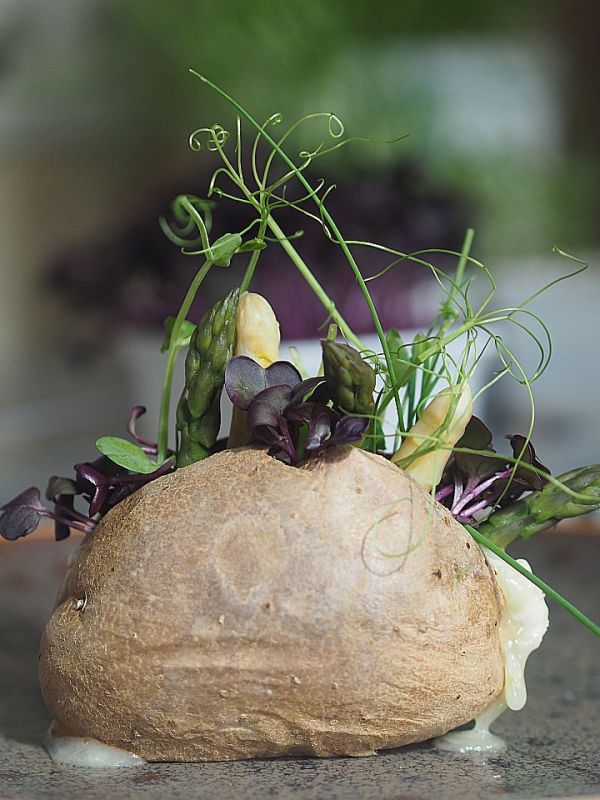 Ofenkartoffel mit eingeträufeltem Ziegenkäse und eingestecktem Spargel und&nbsp;Kräutern